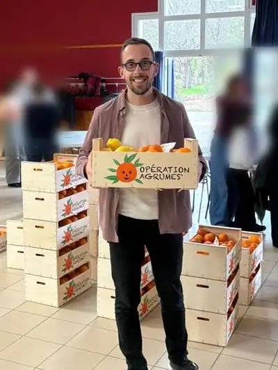 Sylvain, des Écoliers de la Montagne, avec une caisse d'agrumes le jour de la distribution